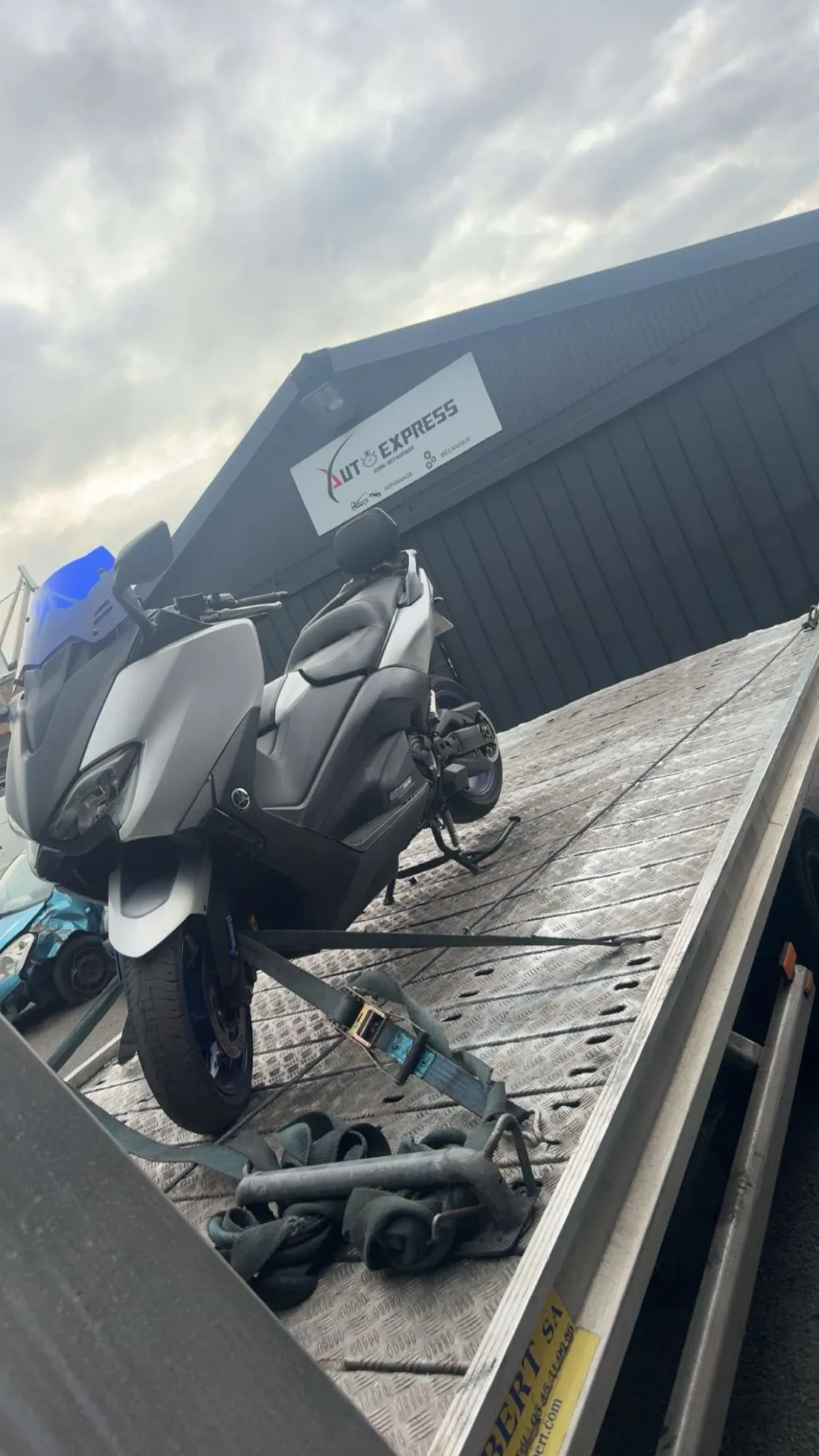 Remorquage scooter Yamaha T-Max sur plateau devant le garage Auto Express